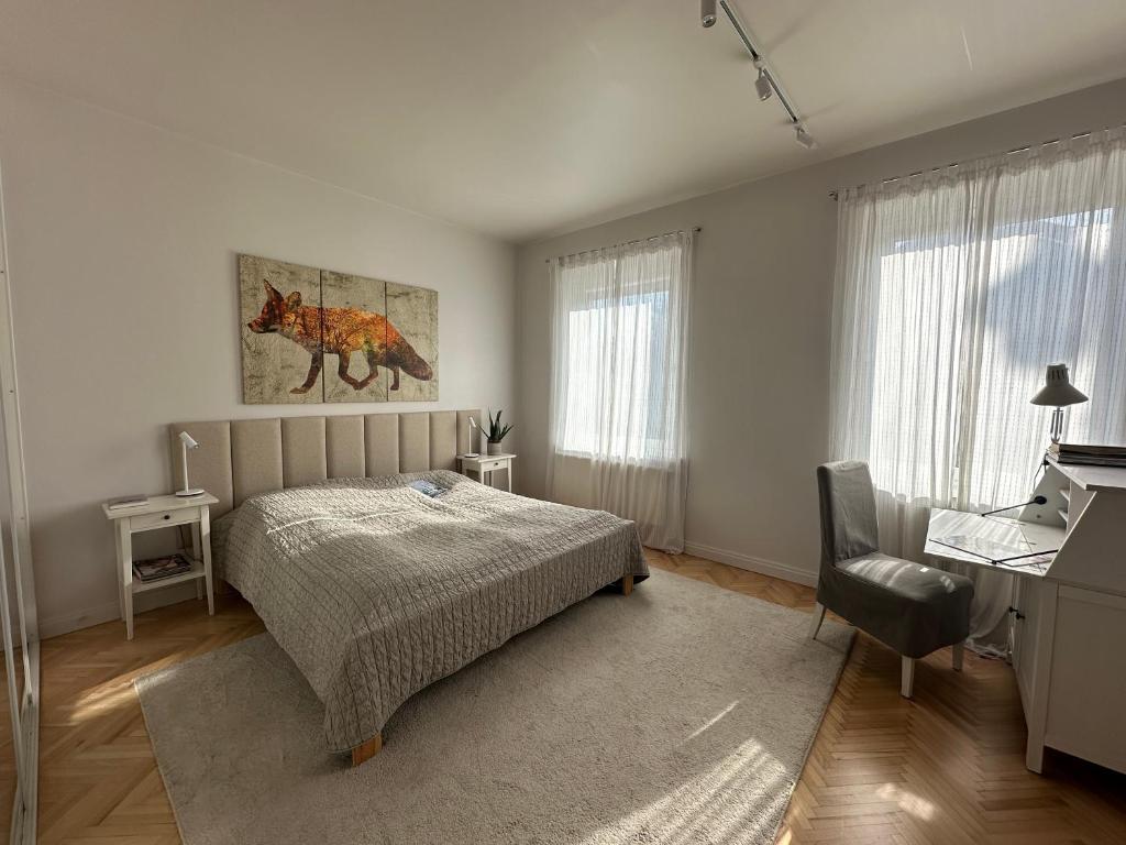 een slaapkamer met een bed, een bureau en ramen bij Blisko Plaży in Sopot