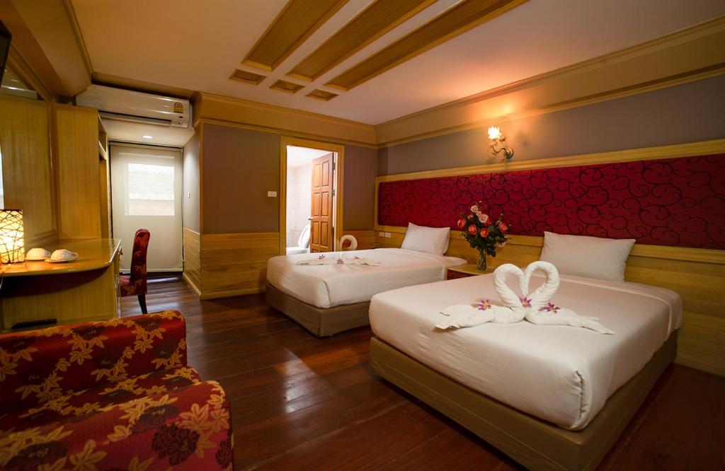 a hotel room with two beds with flowers on them at PEARL RESORT AND HOTEL เพิร์ลรีสอร์ทแอนด์โฮเทล in Ban Bang Phang