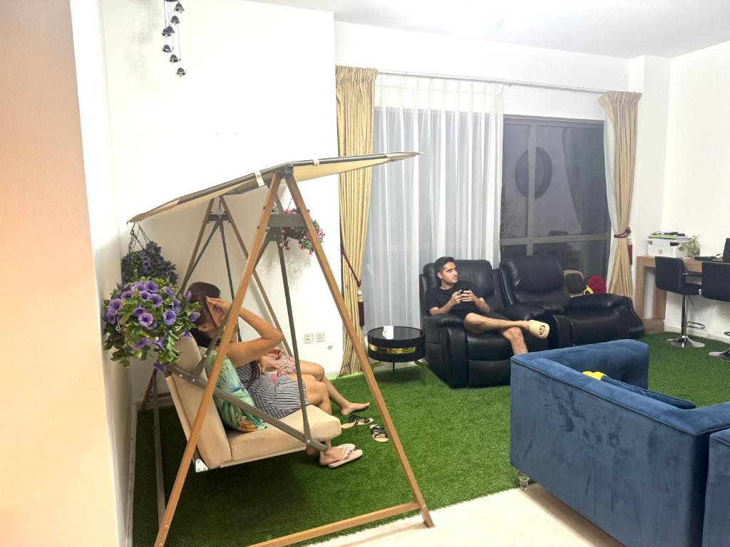Dos personas sentadas en un columpio en una sala de estar en Royal Beach Residences, en Dubái