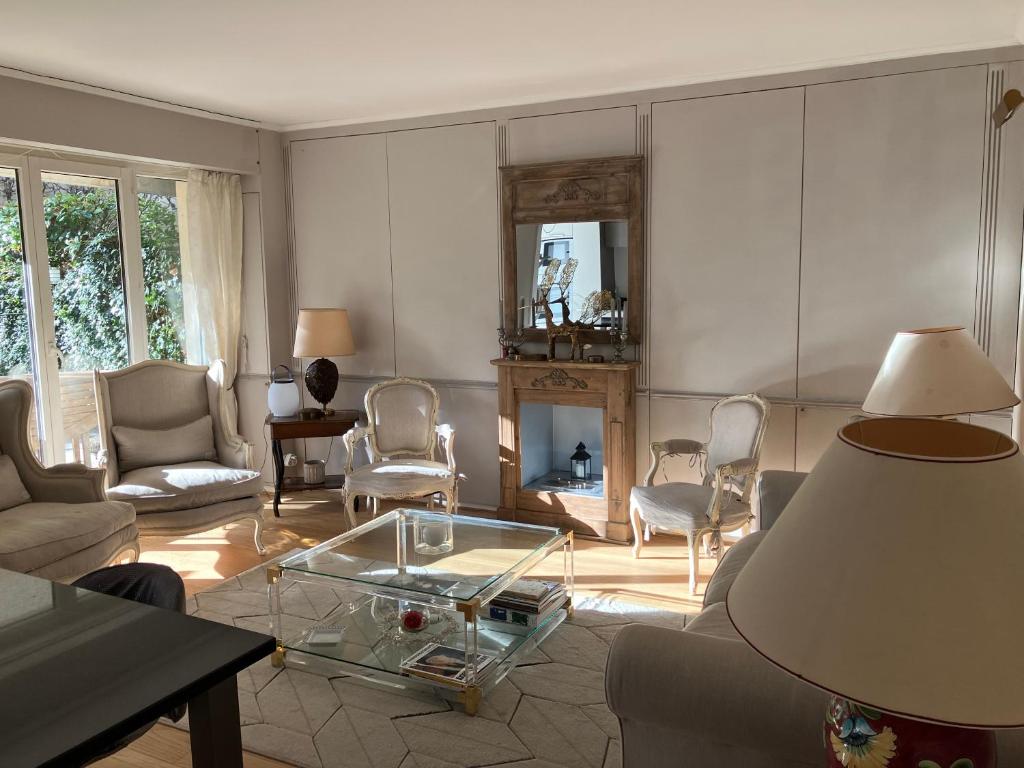 een woonkamer met een bank en een glazen tafel bij Elégant appartement sur jardin à Boulogne in Boulogne-Billancourt