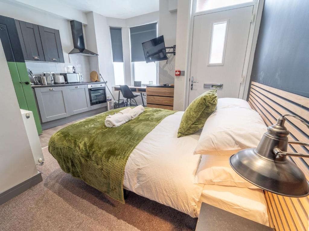 a bedroom with a large bed and a kitchen at Modern cosy retreat Pass the Keys in Beeston