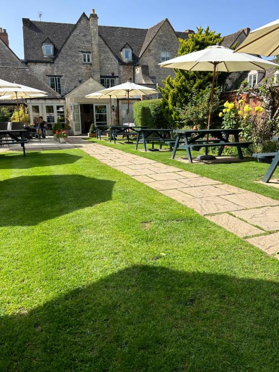 a group of picnic tables and umbrellas in a park at Corinium Hotel & Restaurant in Cirencester