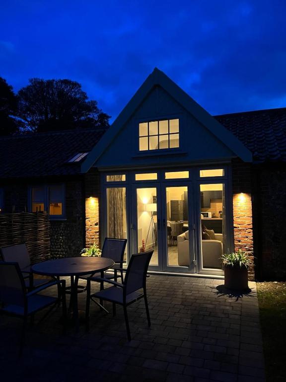 a house with a patio with a table and chairs at Arkle in Kelling