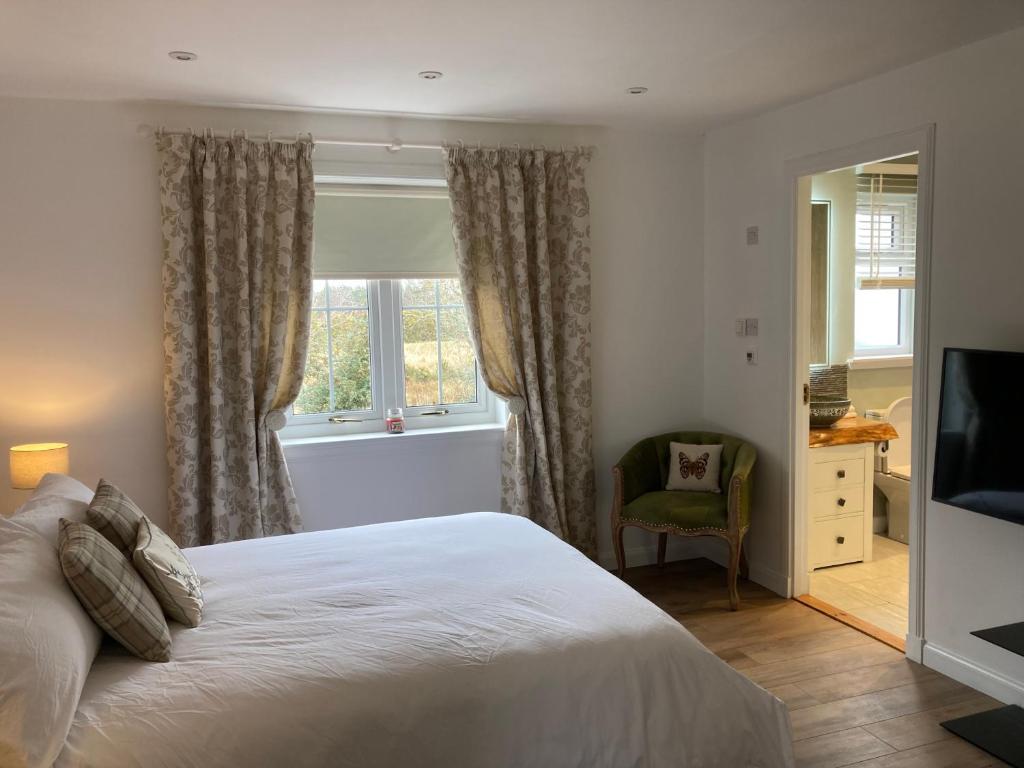 1 dormitorio con cama, ventana y silla en Clashmore Wood en Dornoch