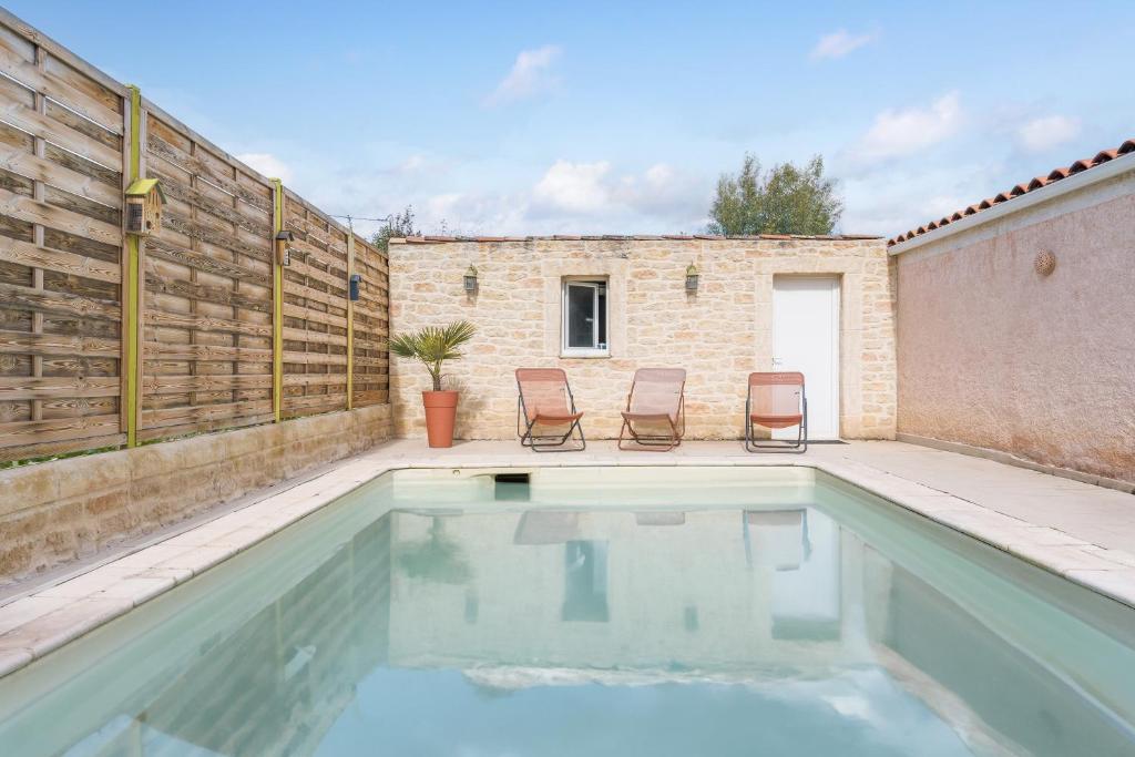 a swimming pool with two chairs next to a brick wall at Villa - Chez Dominique in Manosque