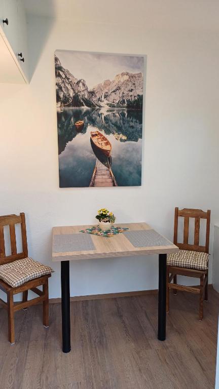 a table with two chairs and a painting on the wall at Zimmer am See in Fußach