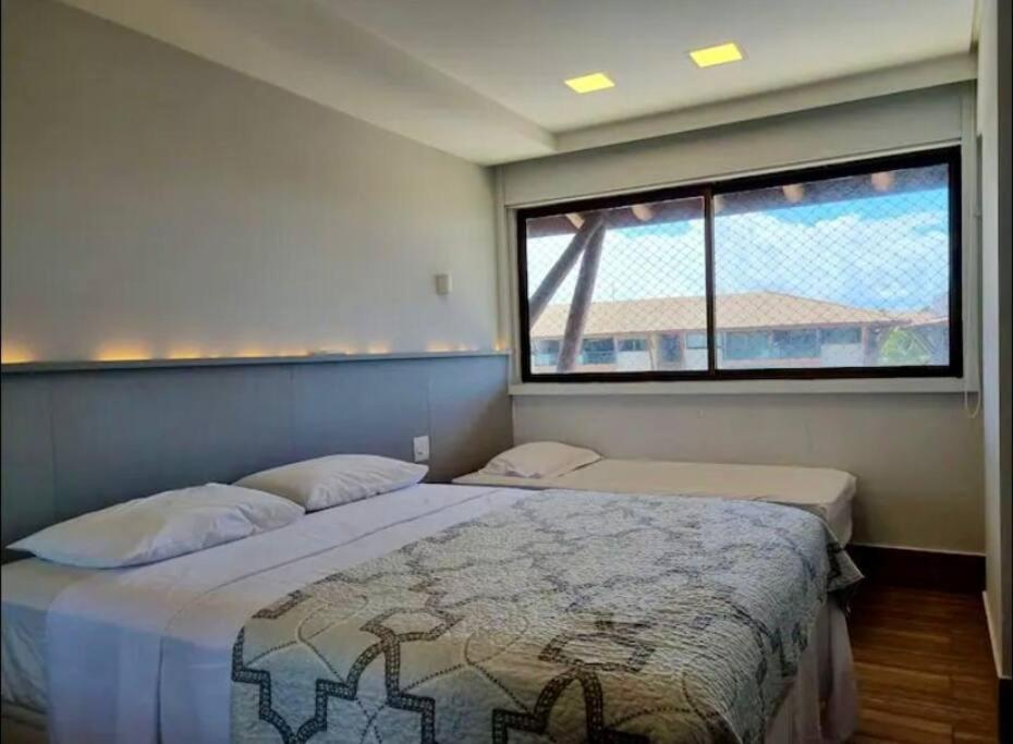 a bedroom with two beds and a large window at Polinésia resort em Porto de Galinhas Muro Alto - Acesso Total ao Samoa Beach Resort in Porto De Galinhas