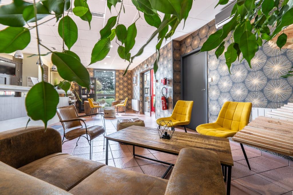 - un hall avec des chaises jaunes et une table dans l'établissement Hotel Restaurant Le Sainte Mere, à Sainte-Mère-Église