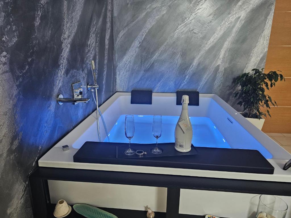 a bath tub with a bottle of wine and two glasses at Blue Hole Jacuzzi Suite e B&B Santeramo in Colle in Santeramo in Colle