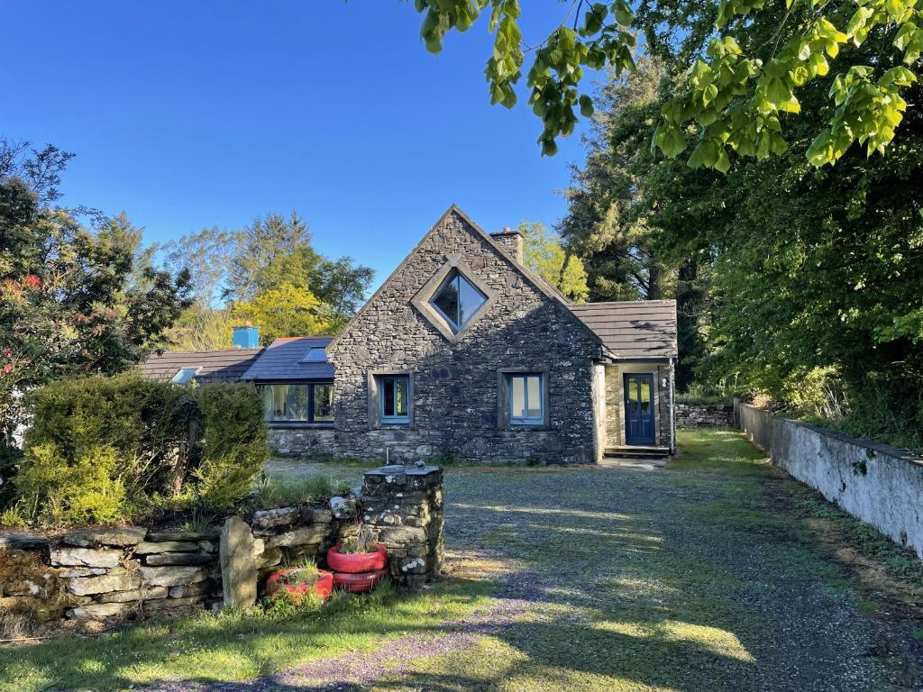 an old stone house with a stone wall in the yard at Ballyroe Accommodation in Leap