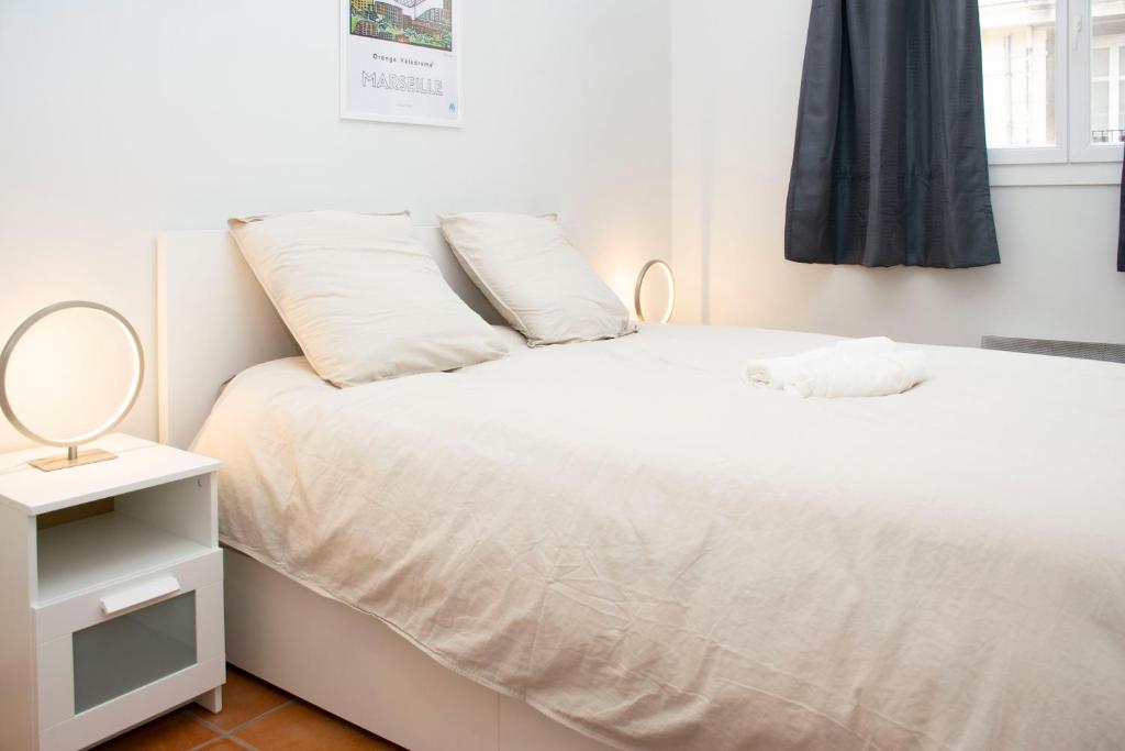 sypialnia z białym łóżkiem i lustrem w obiekcie Appartement au coeur du Vieux-Port w Marsylii