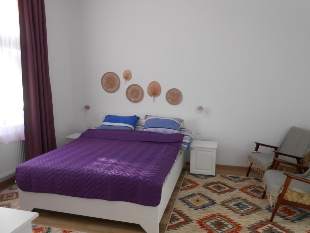 1 dormitorio con cama morada y alfombra en Villa Stoia, en Ocna Sibiului