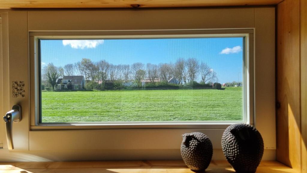 a window with a view of a green field at City Farmers Lodge, a Guesthouse with a skyline view in Rural Amsterdam in Amsterdam