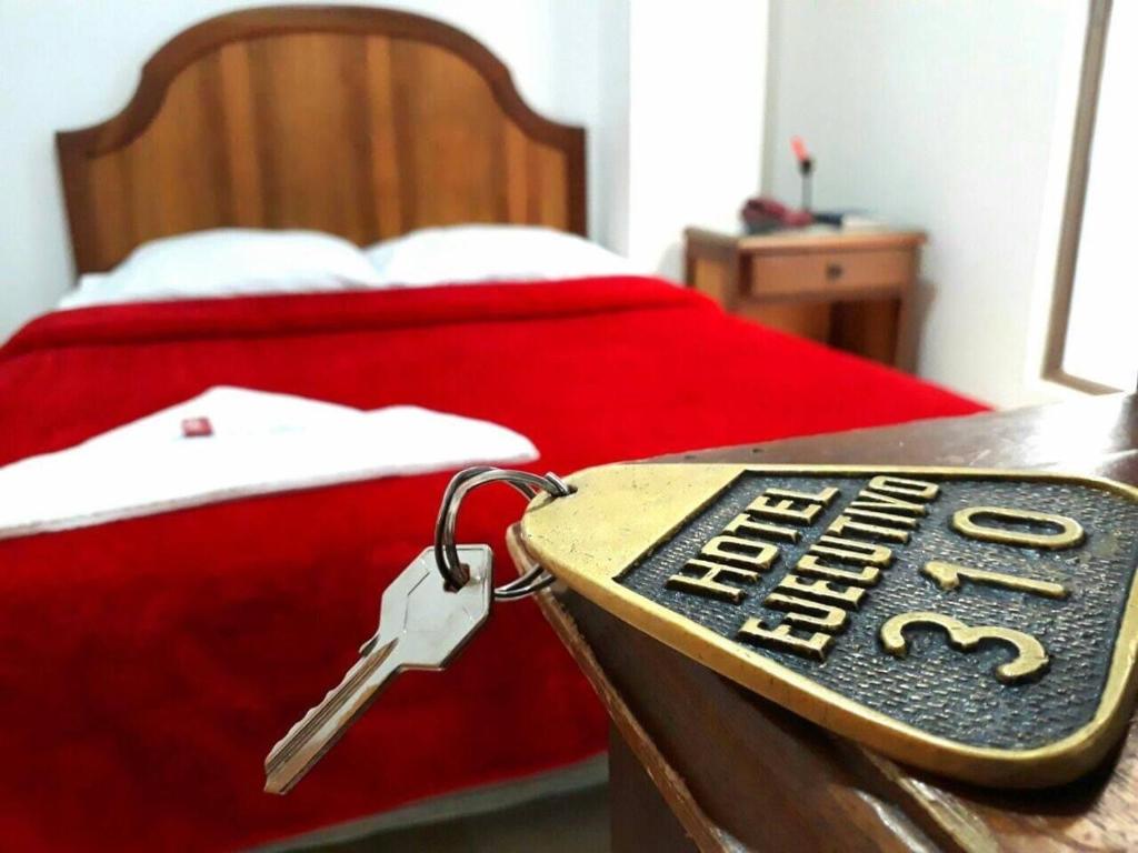 Una llave en una mesa junto a una cama en HOTEL EJECUTIVO, en Pitalito