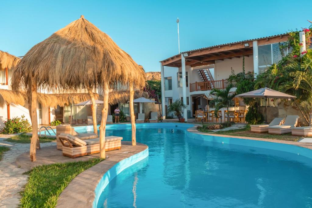um resort com uma piscina com cadeiras e guarda-sóis em Hotel Beso de Sal Resort em Colán
