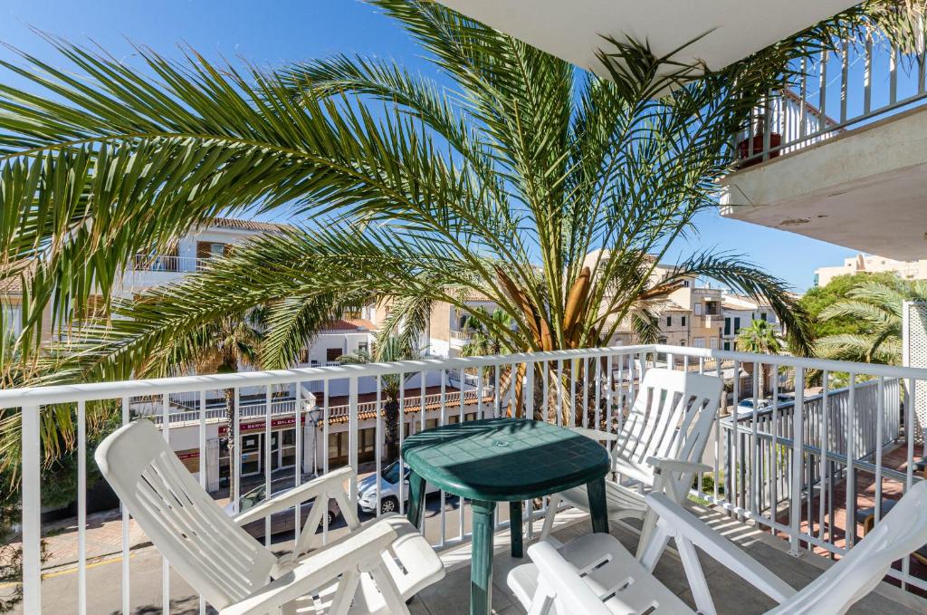 uma varanda com cadeiras, uma mesa e uma palmeira em YourHouse Monges apartment with balcony em Can Picafort