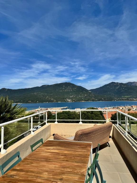 a balcony with a wooden table and a view of the water at Appartement face à la mer 4 pers in Propriano