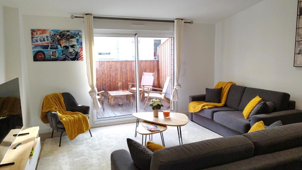 ein Wohnzimmer mit einem Sofa und einem Tisch in der Unterkunft Appartement avec terrasse in Libourne
