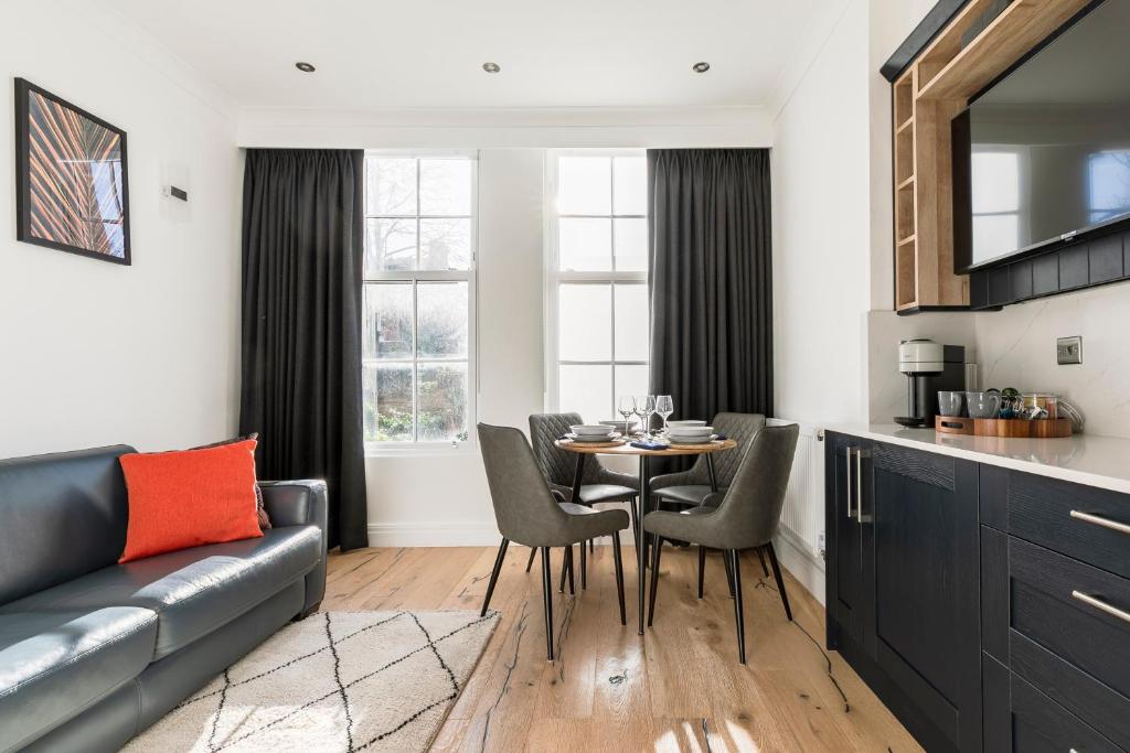 a living room with a couch and a table with chairs at Modern Apartment, 2 Stops to Central London, Netflix, Smart Locks in Ealing