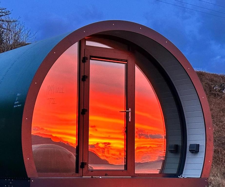 a dome house with a sunset in the window at Loch Assapol Pod in Pennyghael
