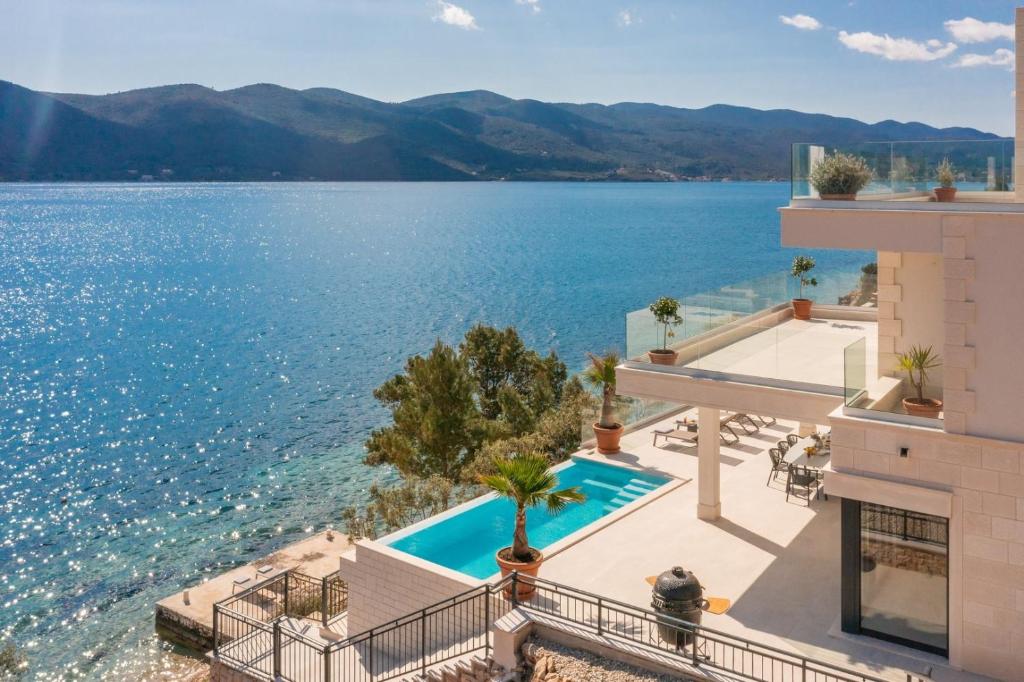 een afbeelding van een gebouw met uitzicht op het water bij Villa Maris, 10m from beach, infinity pool in Kučište