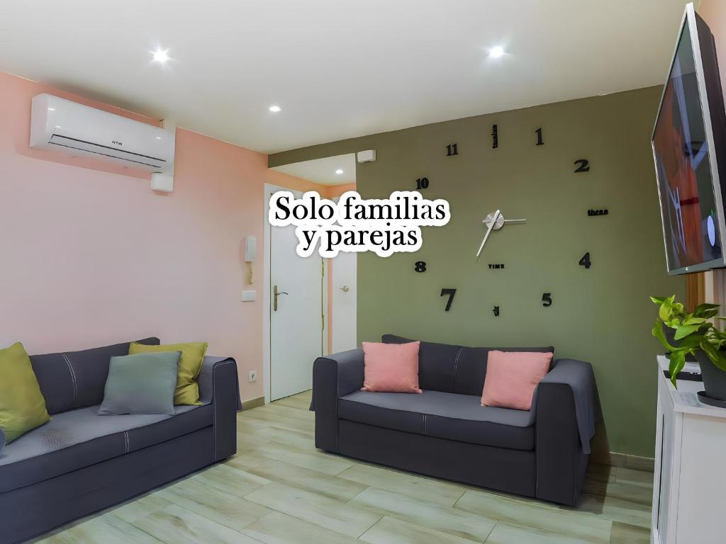 una sala de estar con 2 sofás y un reloj en la pared en Apartamento en Barcelona para familias y parejas en Barcelona