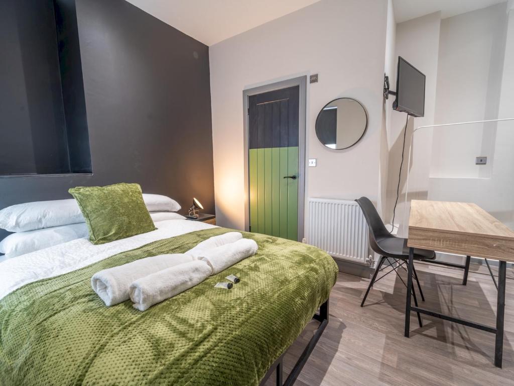 a bedroom with a green bed with a desk and a chair at Cosy retreat Pass the Keys in Beeston