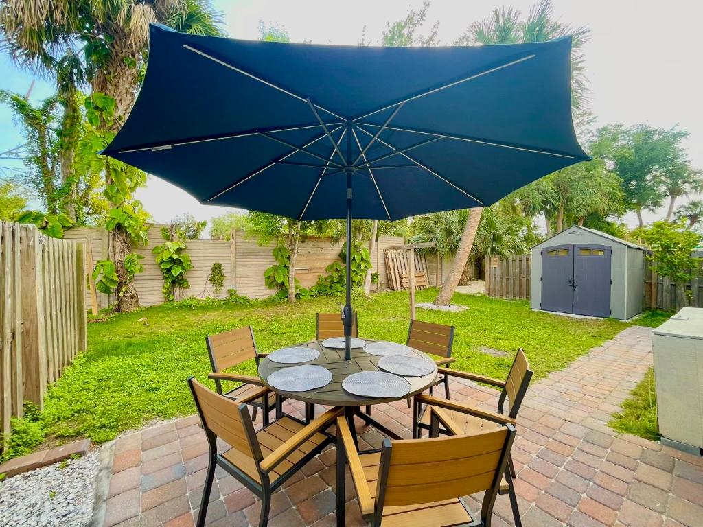 a table and chairs with a blue umbrella at Fort Myers Beach Escape 3 Miles Away Sleep 7 in Fort Myers Beach