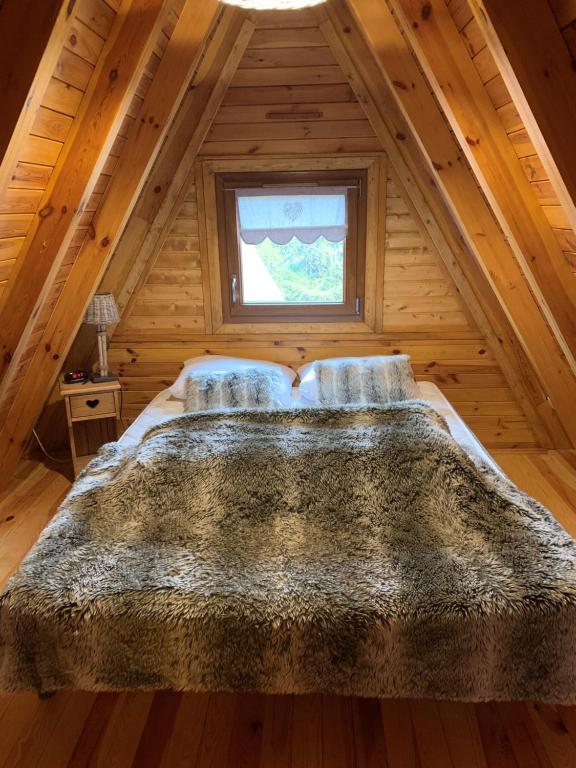 Cama grande en habitación de madera con ventana en Chalet 8 à 10 couchages en Le Dévoluy