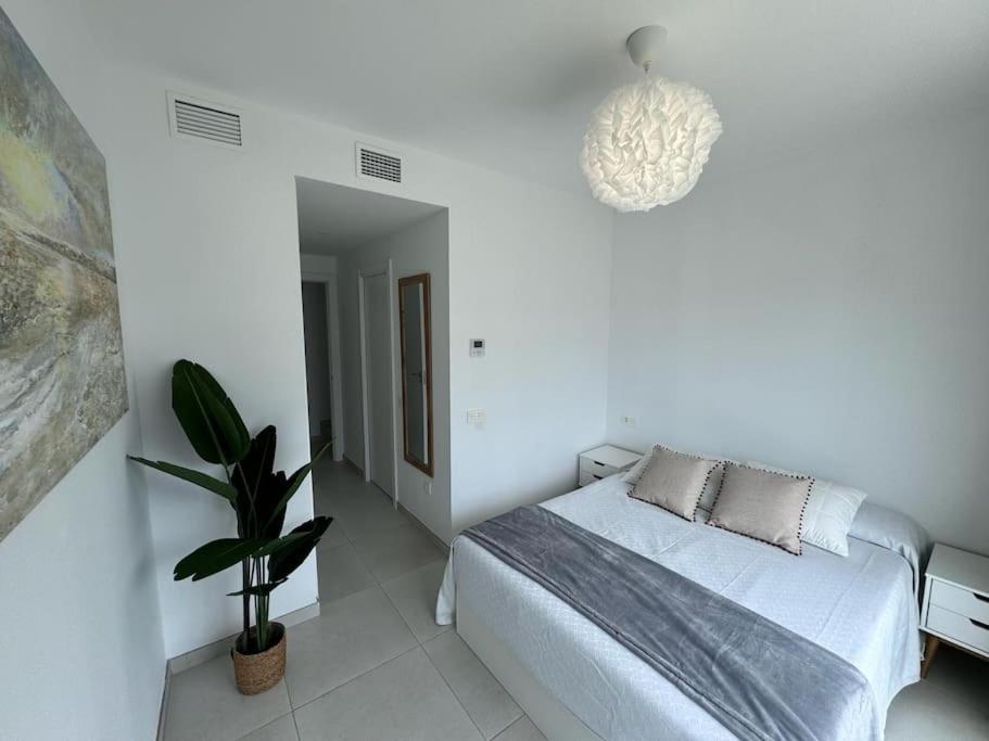a white bedroom with a bed and a potted plant at Duplex penthouse close to the beach in Costa Ballena