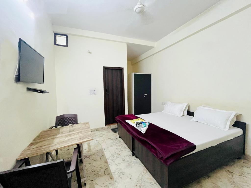 Schlafzimmer mit einem Bett, einem Tisch und einem TV in der Unterkunft Hotel In North Campus in Neu-Delhi