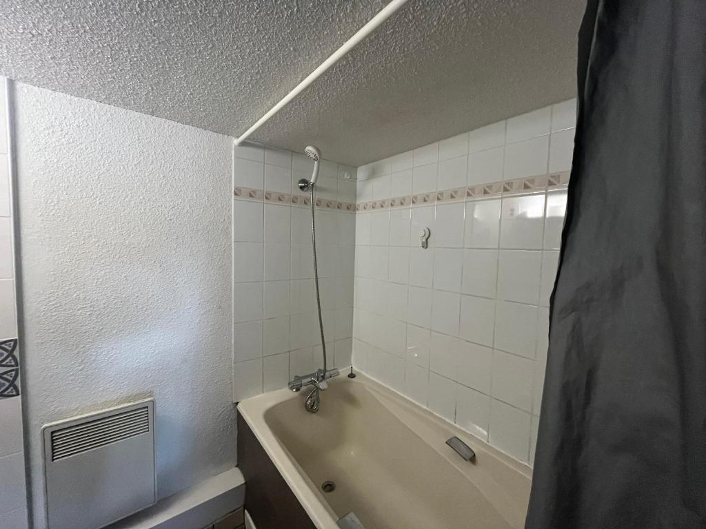 a white bathroom with a tub and a shower at Le Génépi in Taninges