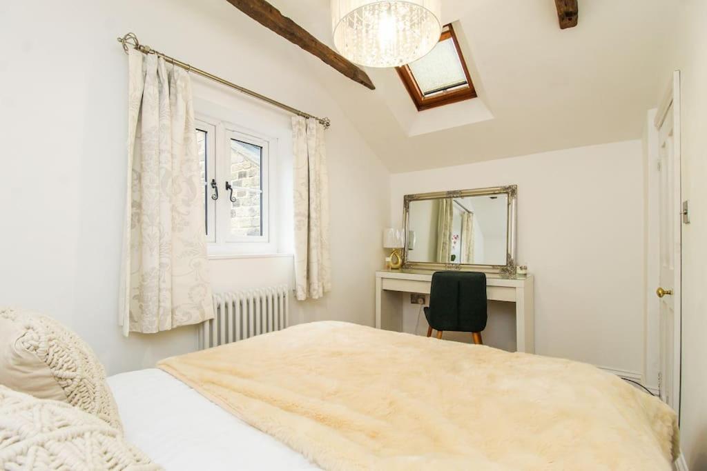 Schlafzimmer mit einem Bett, einem Schreibtisch und einem Spiegel in der Unterkunft Millstone Cottage Newmillerdam in Hill Top