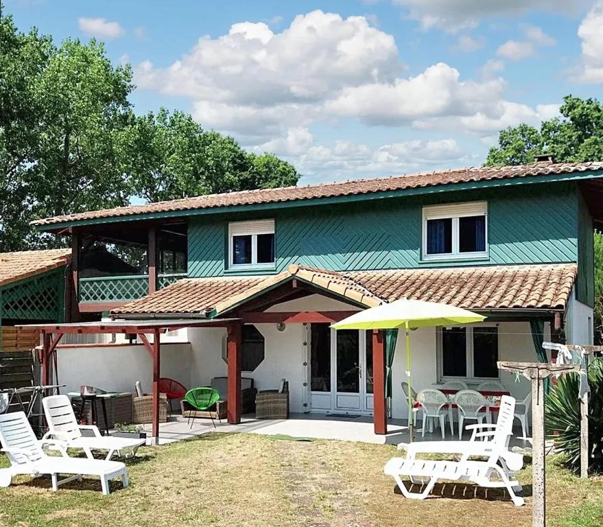 une maison avec un groupe de chaises et un parasol dans l'établissement Maison de 3 chambres avec jardin clos et wifi a Vielle Saint Girons, à Vielle-Saint-Girons