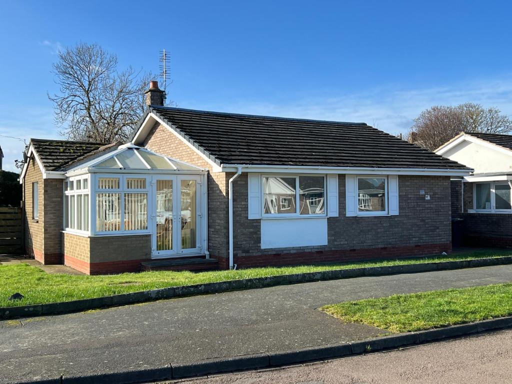 a brick house with white windows on a street at Dawson's Corner Retreat in Beadnell