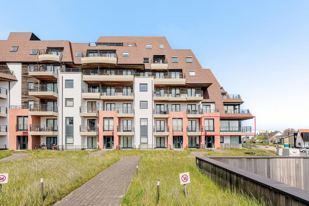 un gran edificio de apartamentos con una pasarela delante de él en Long Island 21 A1 G, en Oostduinkerke