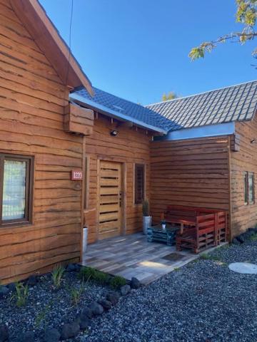 Cabaña de madera con porche y puerta de madera en Hostal Entre Los Lagos en Villarrica