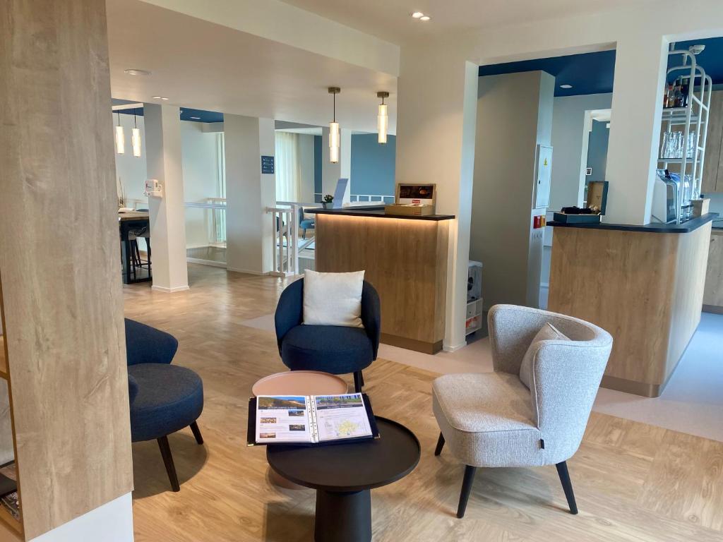 a waiting room with chairs and a table with a tablet at Quality Hotel La Marebaudière Vannes Centre in Vannes