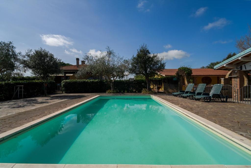 a swimming pool in a yard with two chairs at Agriturismo Il Poderino in Grosseto