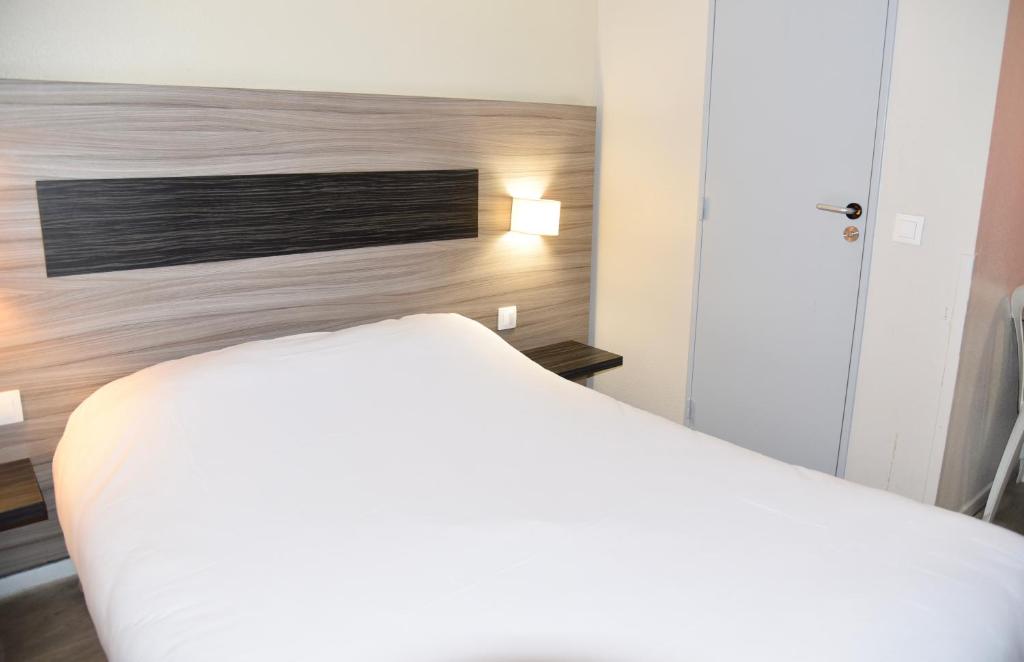 um quarto com uma cama branca e uma parede em Hotel du Triangle em Talange