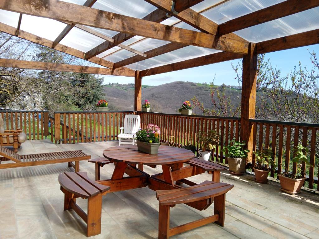 une pergola en bois avec une table et des bancs sur une terrasse dans l'établissement La Bergerie de Lavernhe, à Connac