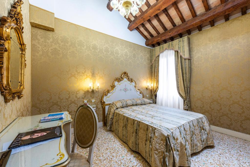 a bedroom with a bed and a table and a window at Hotel Ca' Dogaressa in Venice