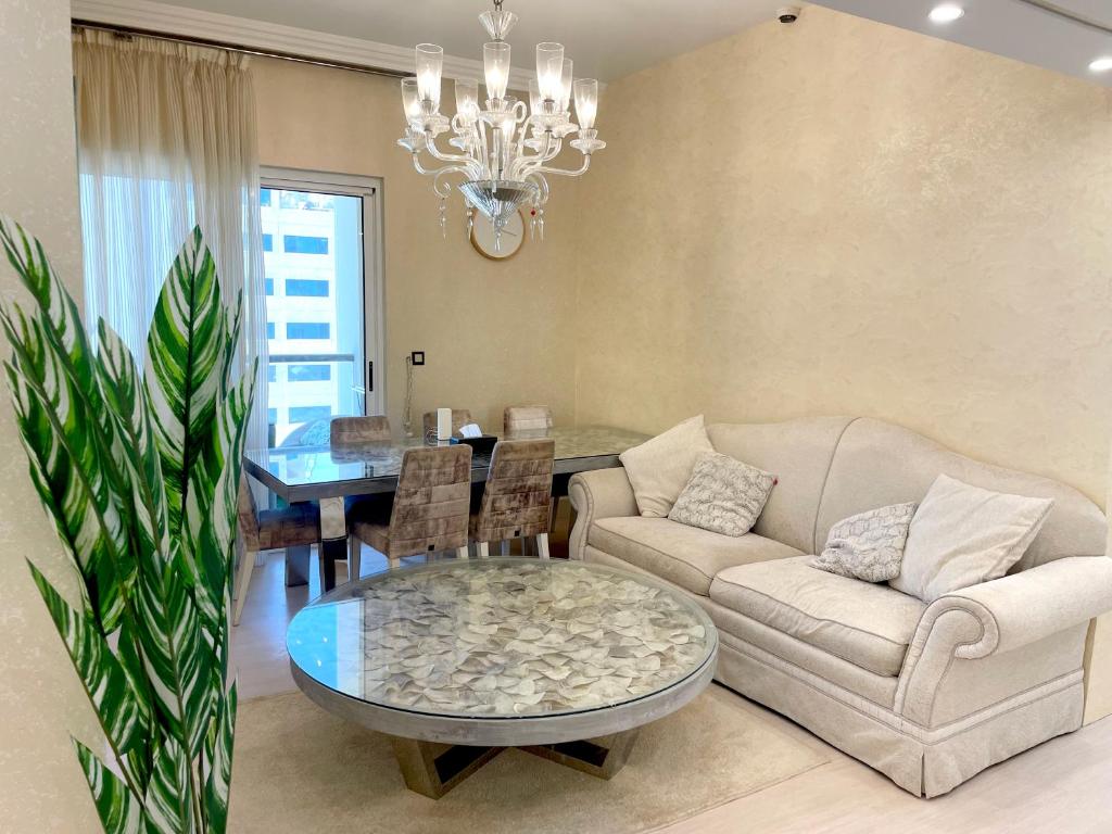 a living room with a couch and a table with a chandelier at ROYAL BEACH RESIDENCES 2 in Dubai