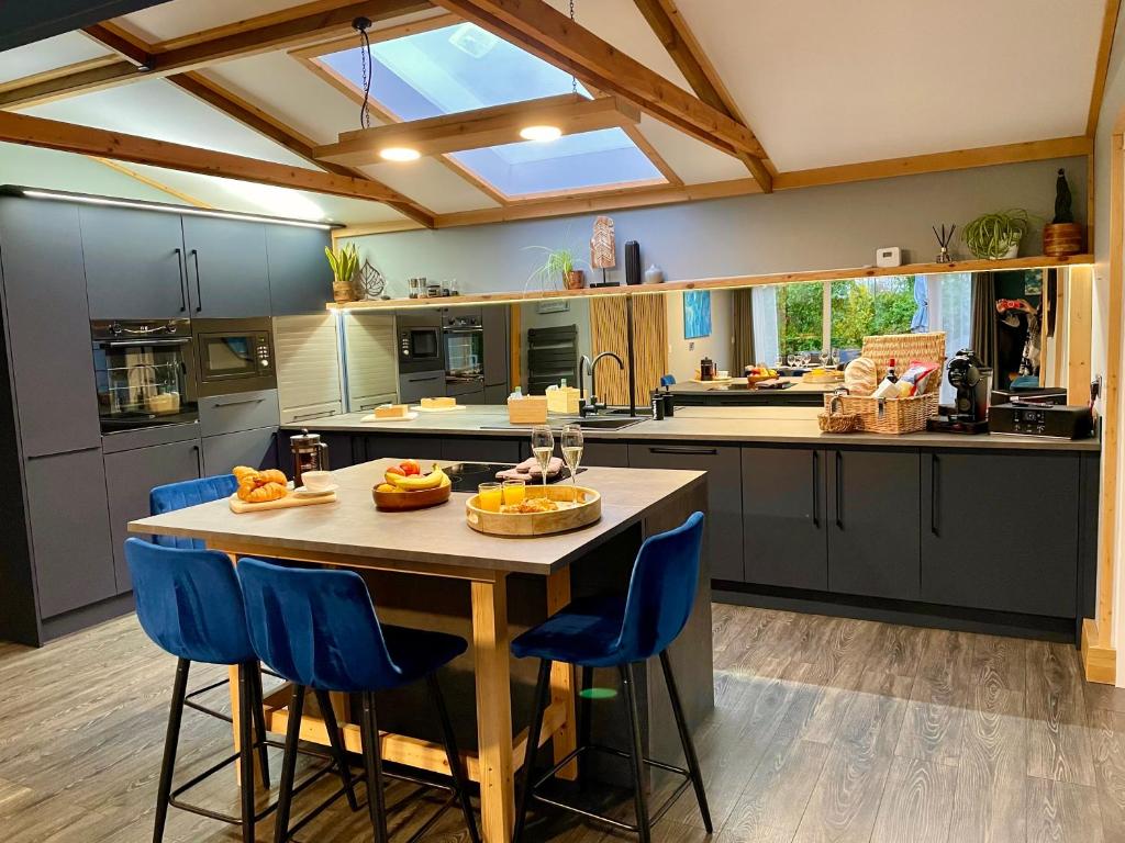 a kitchen with a wooden table and blue chairs at Luxury lodge, foot of South Downs nr beach in Ferring