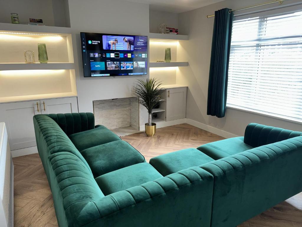a living room with a green couch and a tv at Impeccable 3-Bed House in Walsall in Walsall