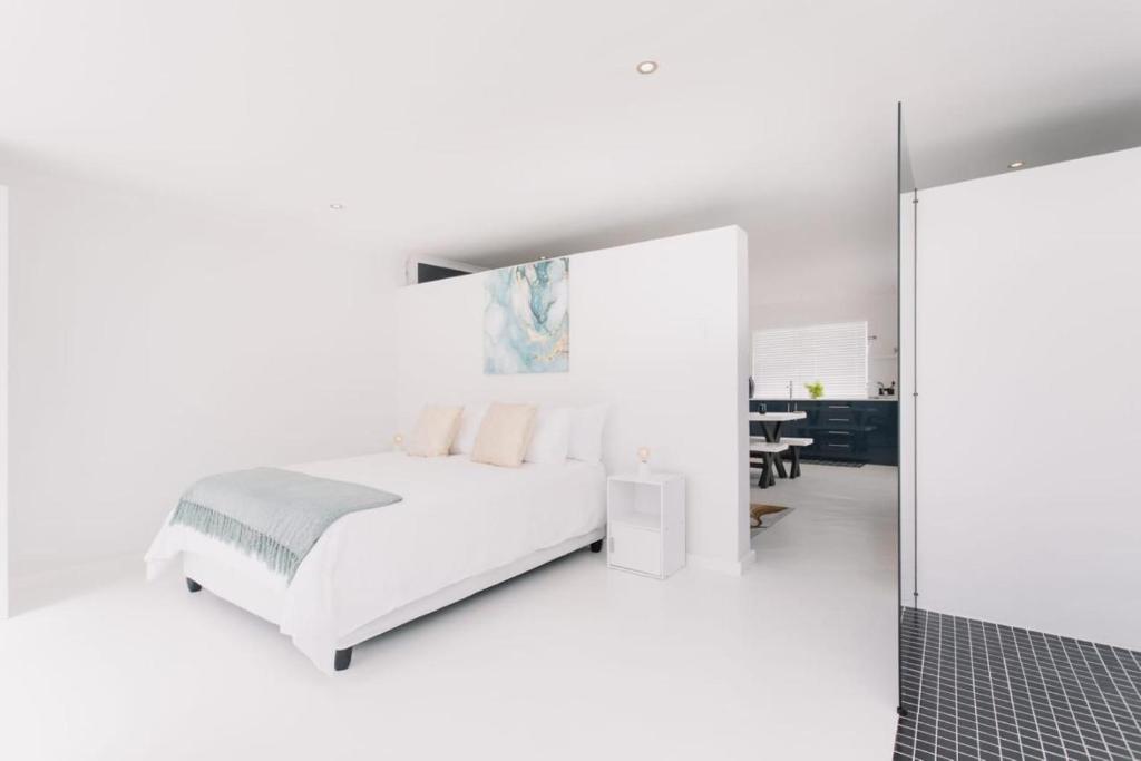 biała sypialnia z łóżkiem i lustrem w obiekcie DMK GUESTHOUSE 2 w Kapsztadzie