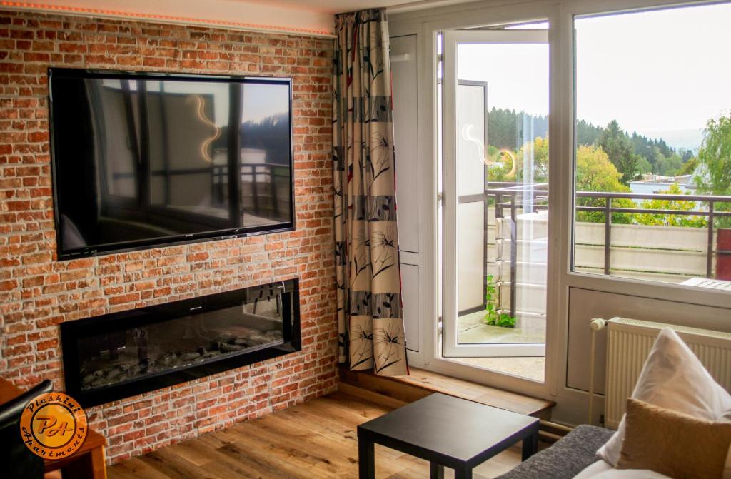 a living room with a fireplace and a tv on a brick wall at Pleskini Apartment in Sankt Englmar