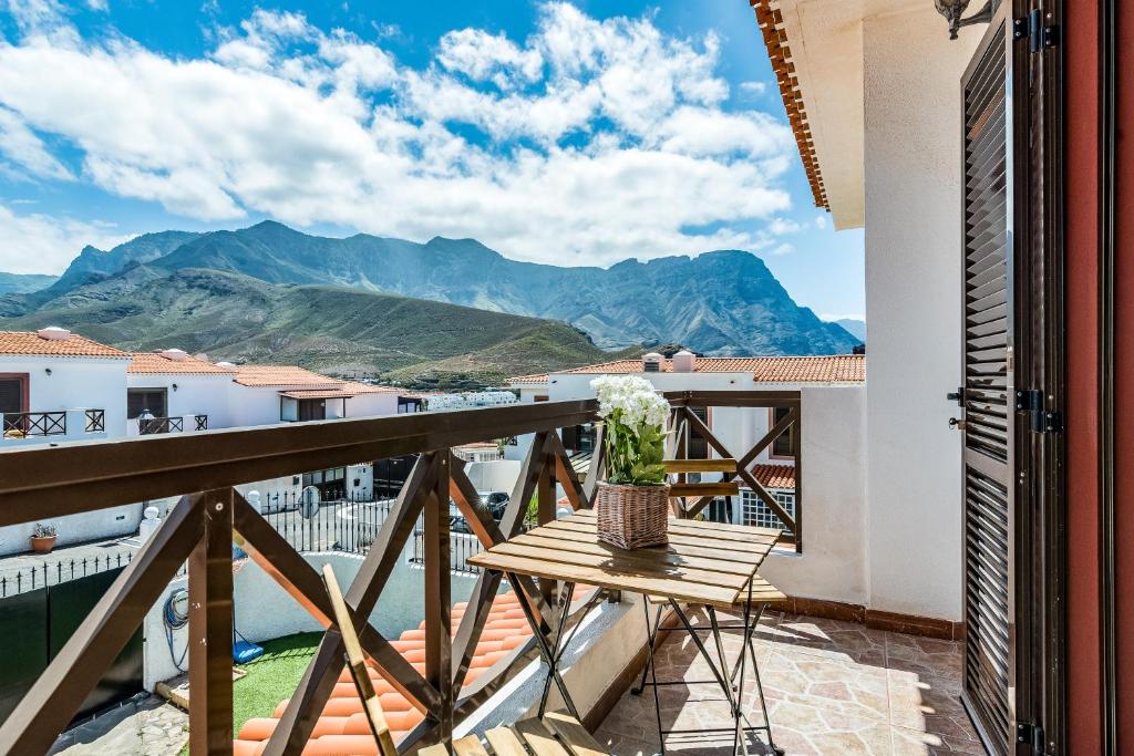 einen Balkon mit einem Tisch und Bergblick in der Unterkunft Home2Book Charming House Agaete, BBQ & Garden in Agaete