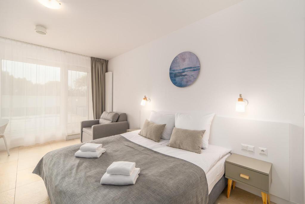 a bedroom with a large bed with two towels on it at Aquamarina Prima 07 Seaside Studio by the BEACH with Terrace by Renters in Międzyzdroje