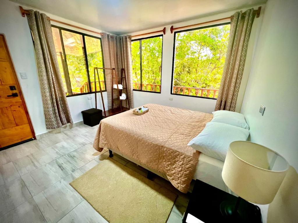 a bedroom with a bed and two large windows at Mayara Hostal in El Zonte